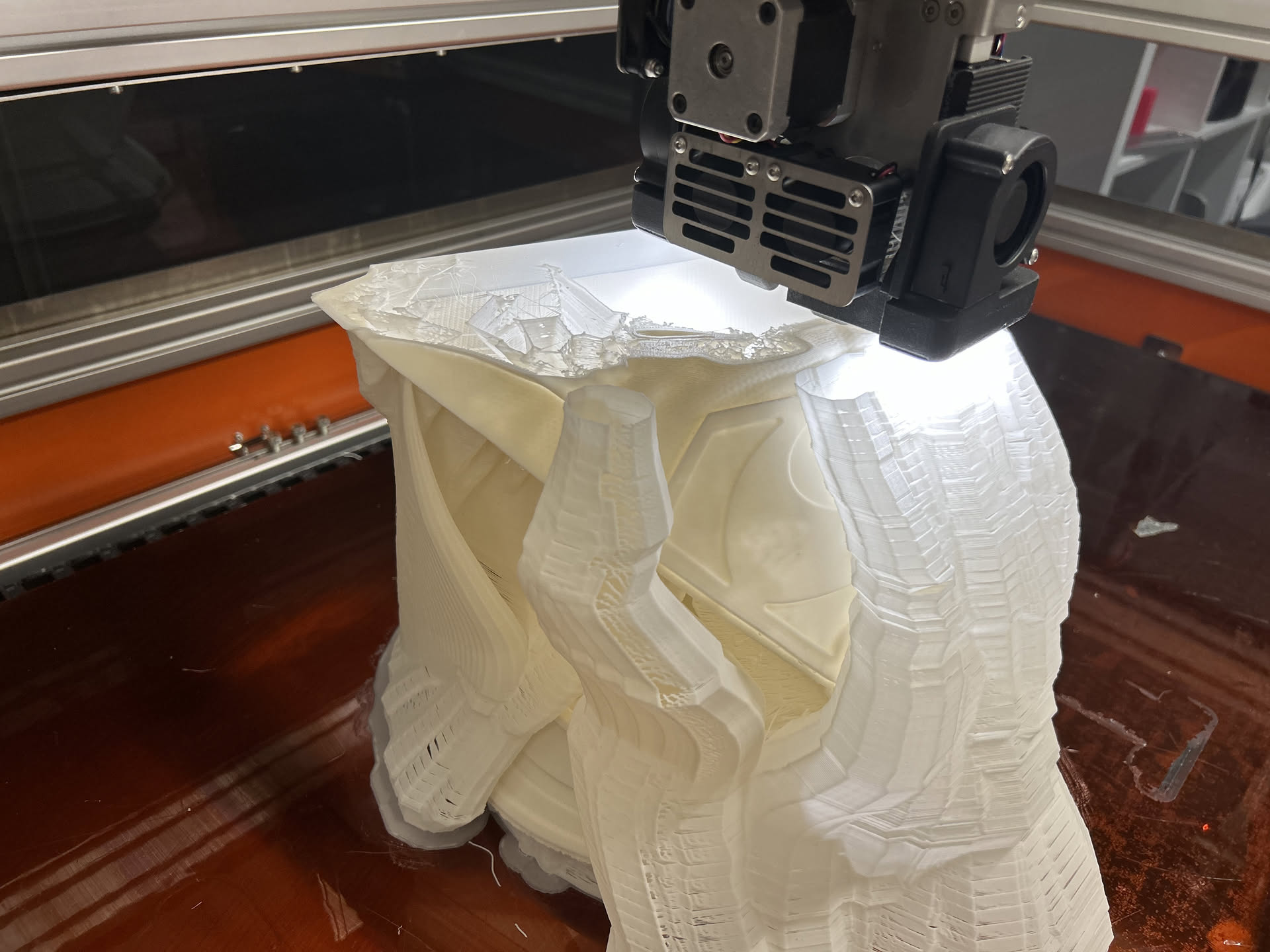 Large-format industrial 3D printer producing a large black part